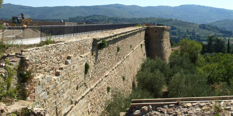 Restauro della Fortezza Medicea di Arezzo: mura in pietra restaurate con torrione e vista sulle colline